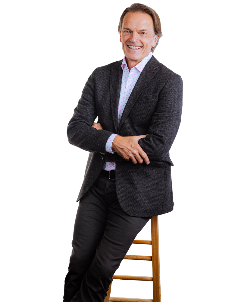 Tom Fleming, Real Estate Broker, sitting on a wooden stool